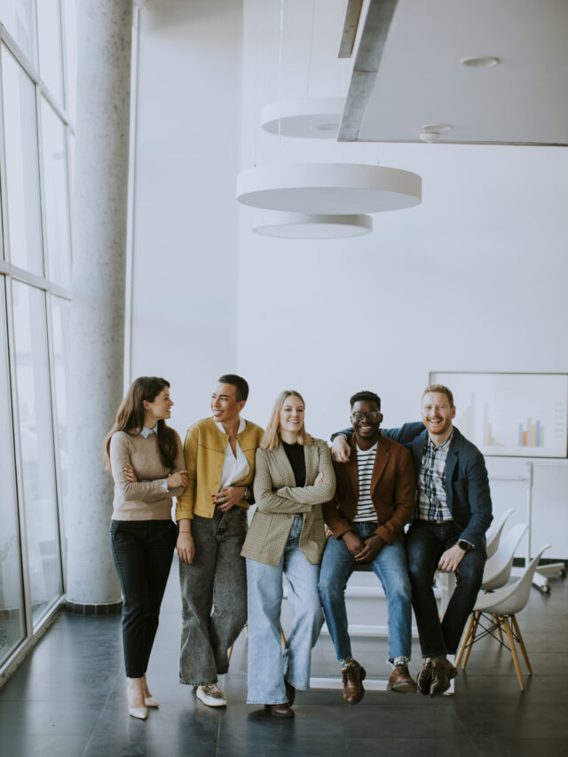 Group of positive businesspeople standing together in the office